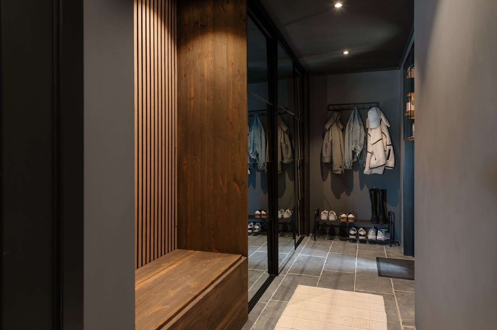 Romslig skyvedørsgarderobe og plassbygget benk med spilevegg i bakkant. Godt lyssatt med downlights i himling Galleribilde