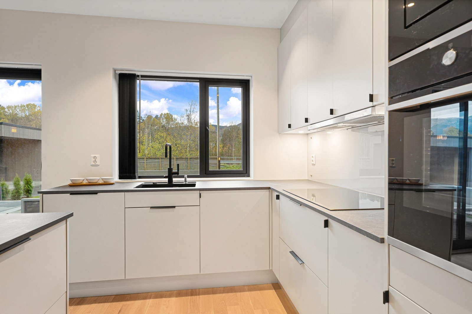 Lekkert kjøkken med slette fronter og laminat benkeplate. Galleribilde