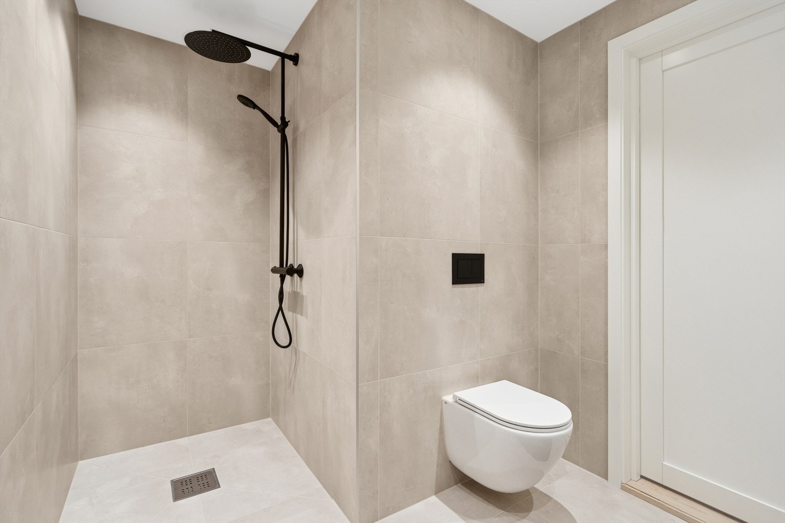 Det vegghengte toalettet bidrar til et ryddig og moderne utseende, mens det sorte dusjgarnityret gir en stilfull kontrast og et sofistikert preg Galleribilde