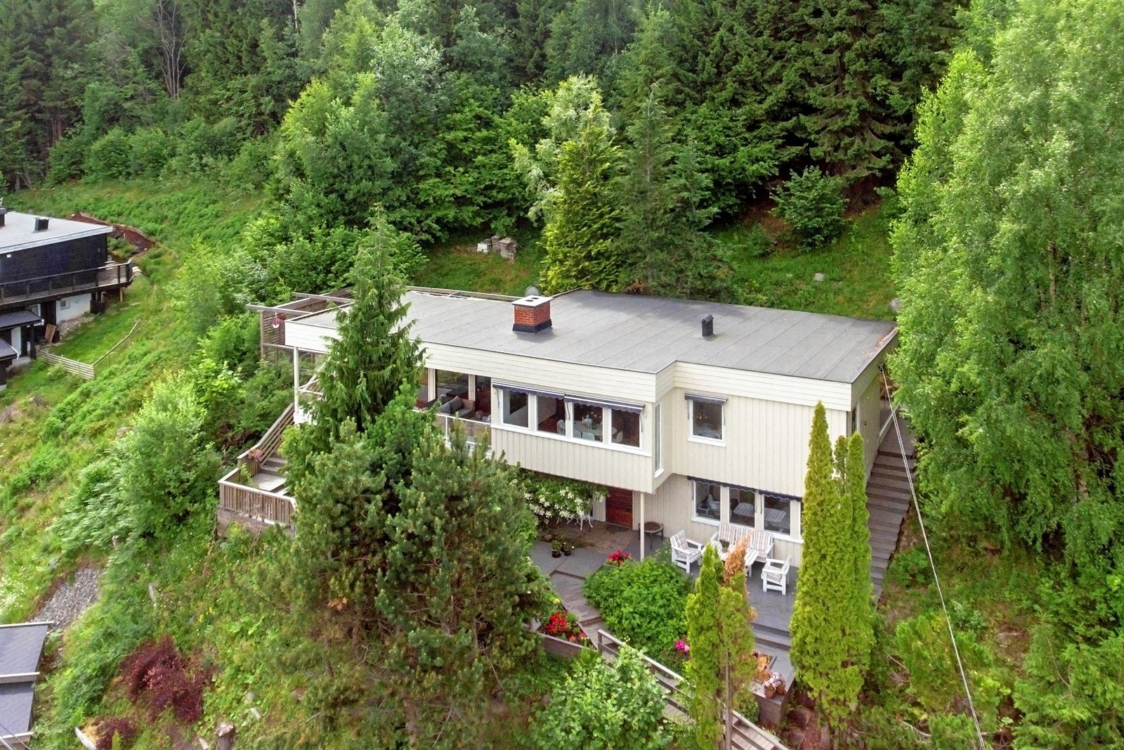 Tomten ligger solrikt til i skrånende terreng og er meget pent opparbeidet med plen, støttemurer, trapper i terrenget, terrasser og beplantning. Galleribilde