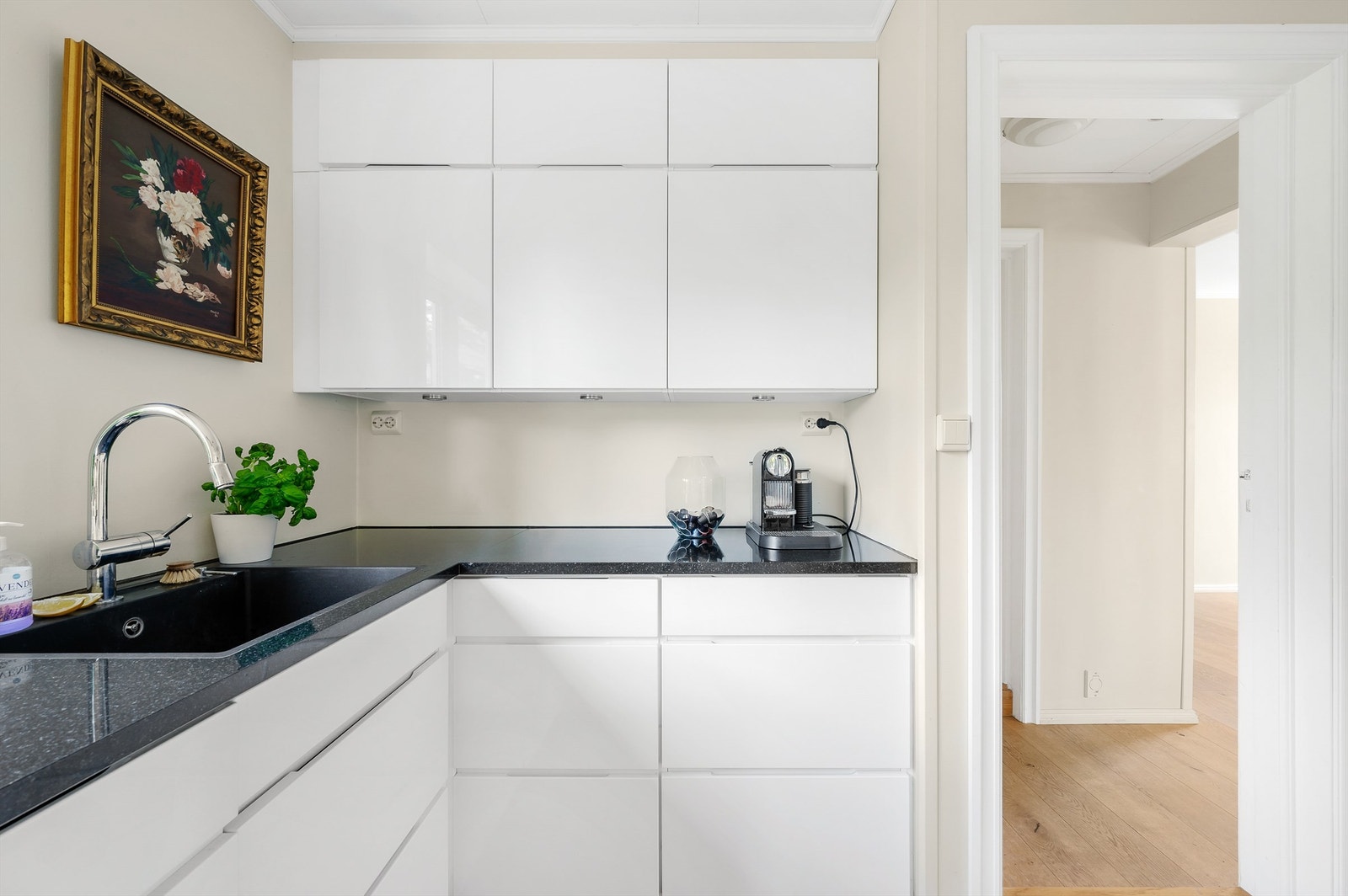 Innredningen har hvite, glatte fronter med gripekant og sort benkeplate i stein med planlimt, sort vaskekum. Galleribilde