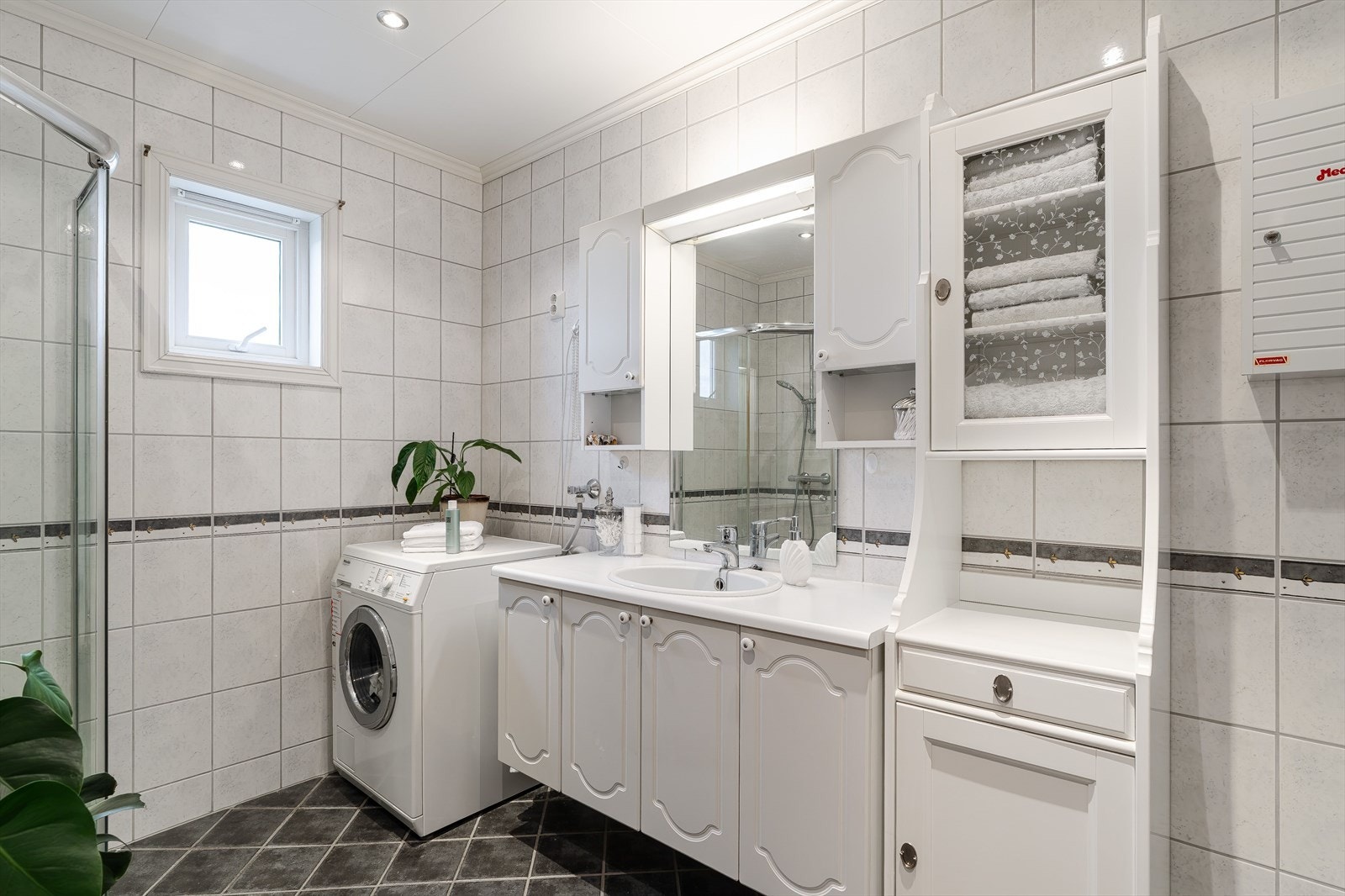 Badet har fliser på både gulv og vegger i både mørke og dempede fargetoner. Galleribilde