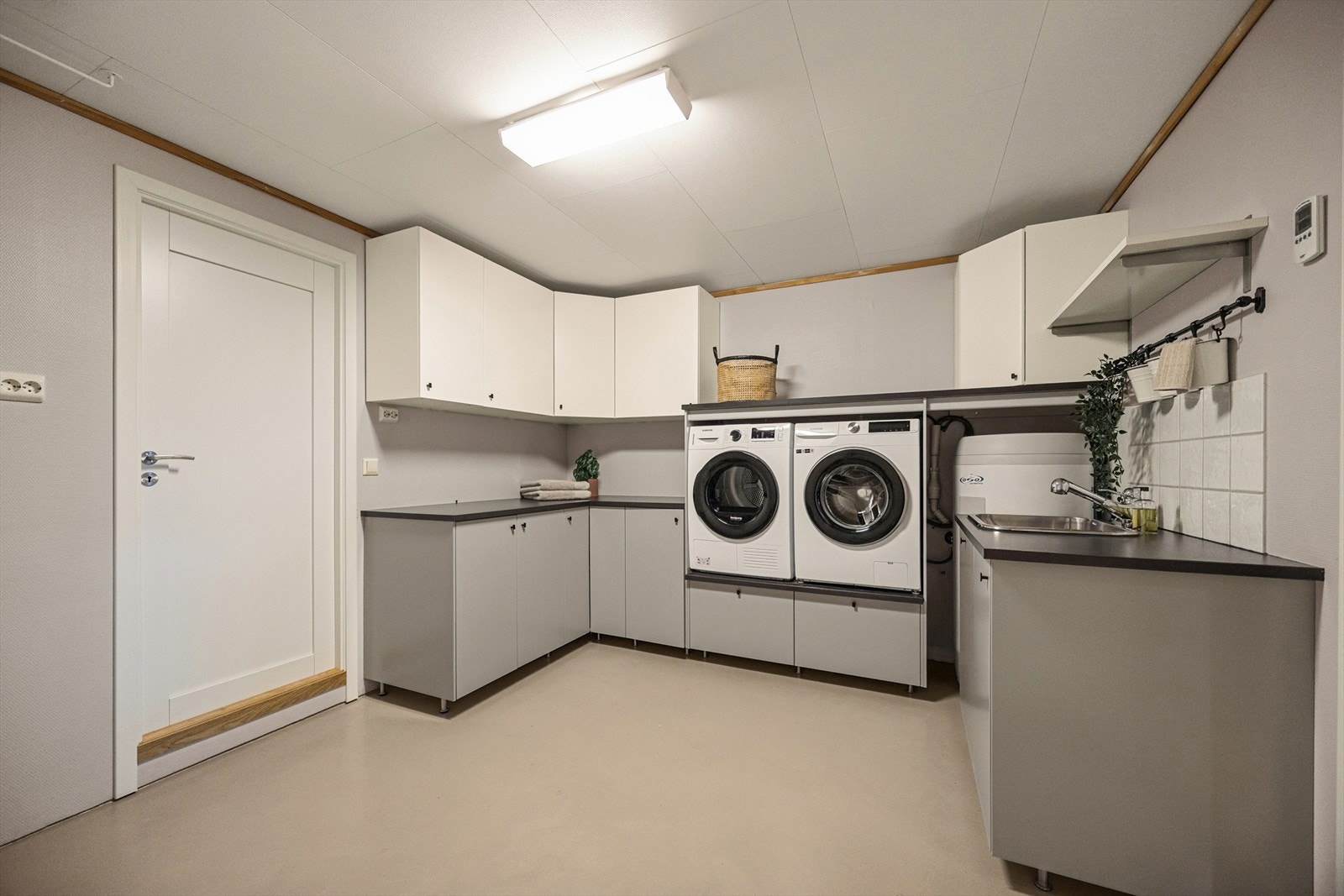 Vaskerommet har malt betonggulv med elektriske varmekabler og har innredning med slette fronter, laminat benkeplate, rustfri kum, samt opplegg for vaskemaskin og tørketrommel. Galleribilde