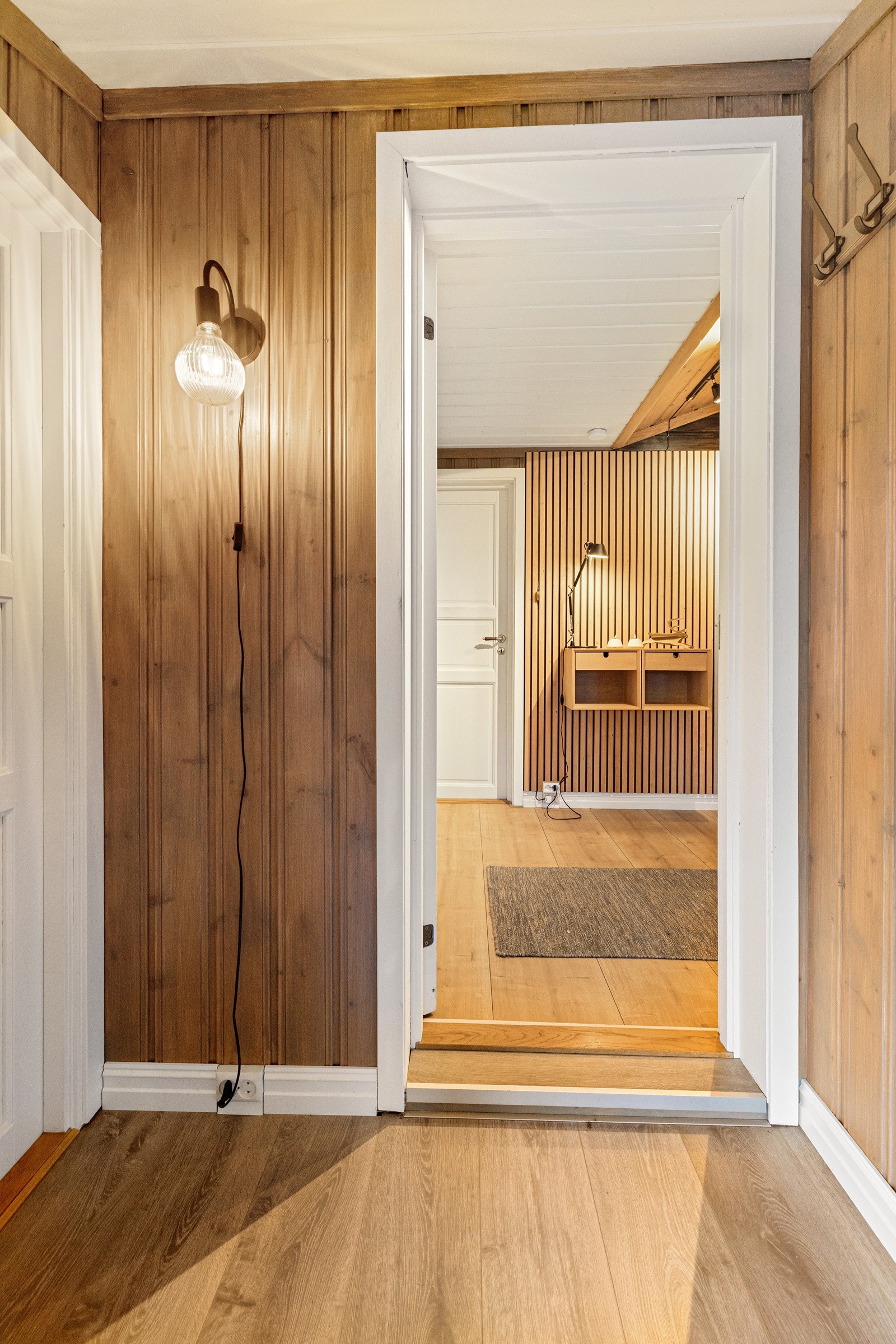 Innbydende entré med gjennomgående bruk av trepanel på vegger og tregulv, som gir et varmt og helhetlig preg. Galleribilde