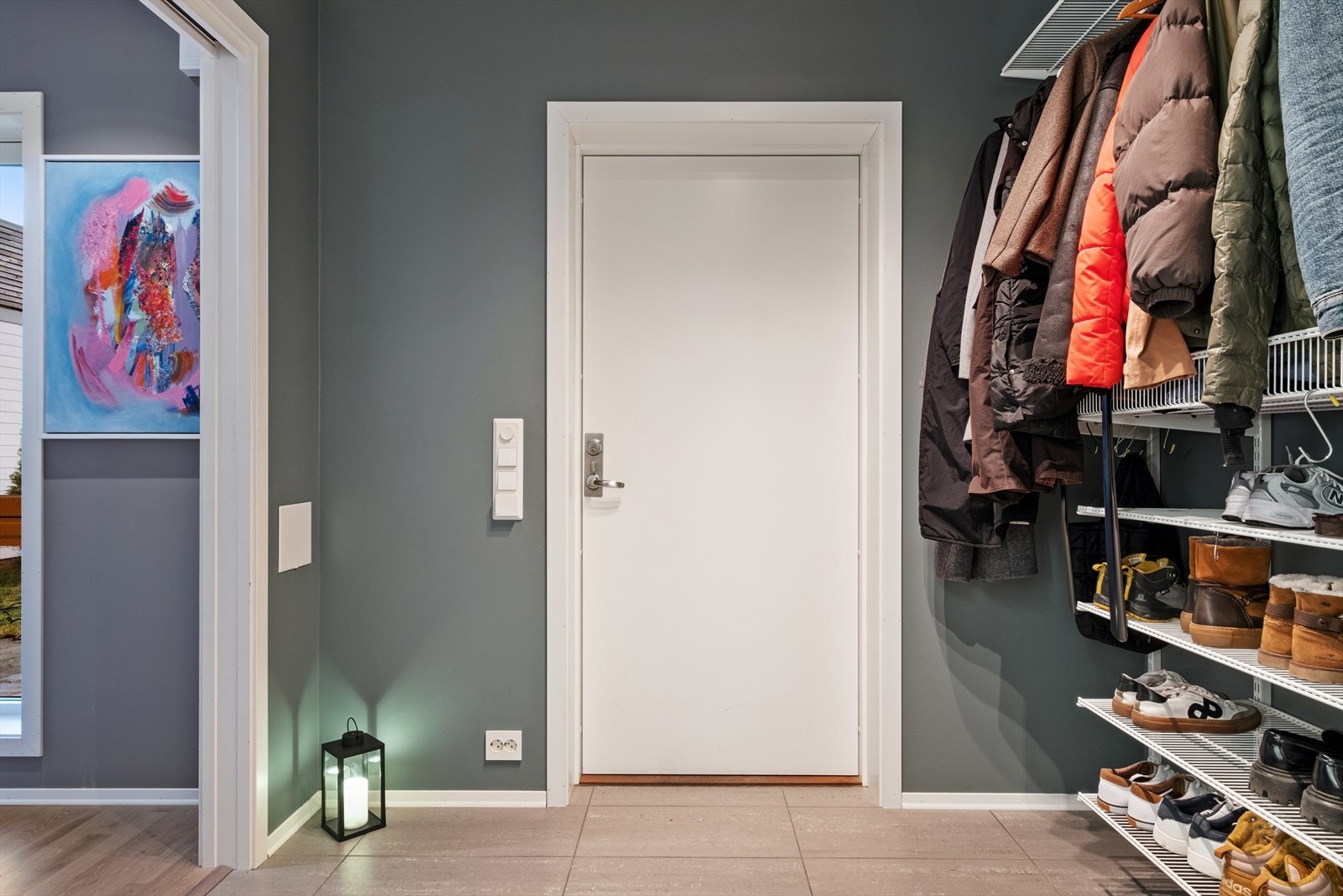 Man ønskes velkommen inn i en flislagt gang på 5 kvm med god hylleplass for yttertøy. Galleribilde