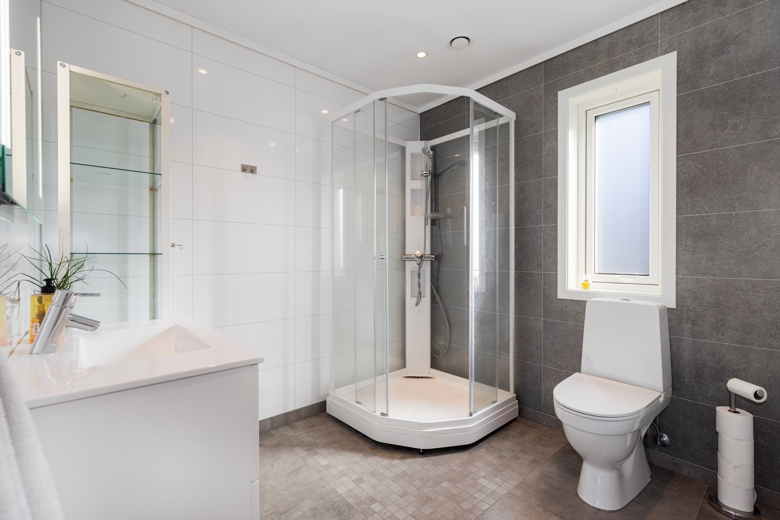 Badet er innredet med toalett, dusjkabinett og servantinnredning med underskuffer og speil over. Galleribilde