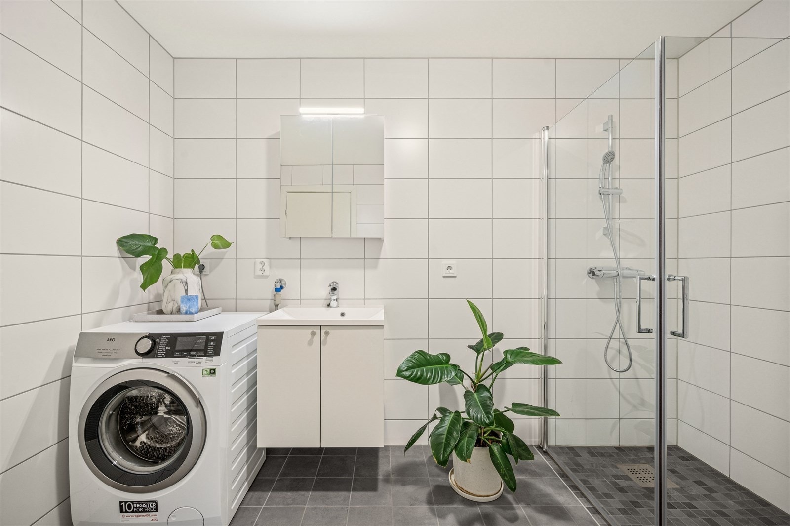 Bad i underetasjen med opplegg for vaskemaskin og vegghengt servantinnredning og dusjhjørne Galleribilde