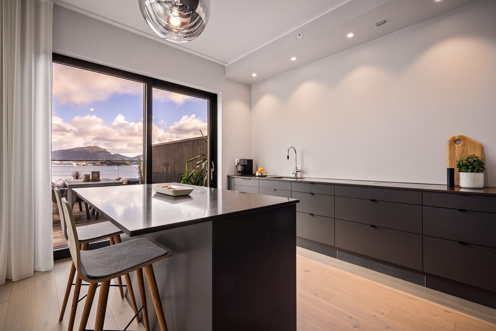 Kjøkkenet, fra Sigdal, finner sin velegnede plass i hjørnet av stuen og er av mørke slette fronter, quartz kompositt benkeplate, stål oppvaskkum og ventilator. Her er også benyttet malte flater over benkeplaten. Galleribilde