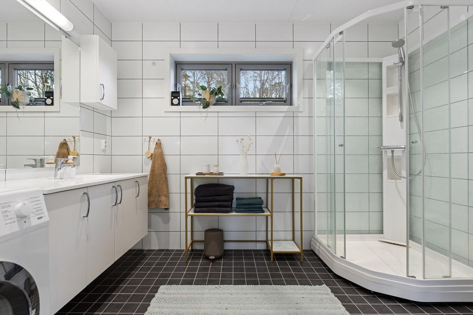 Pent, flislagt baderom med moderne servant elegant nedfelt i praktisk skapinnredning. Dusjkabinett. Galleribilde