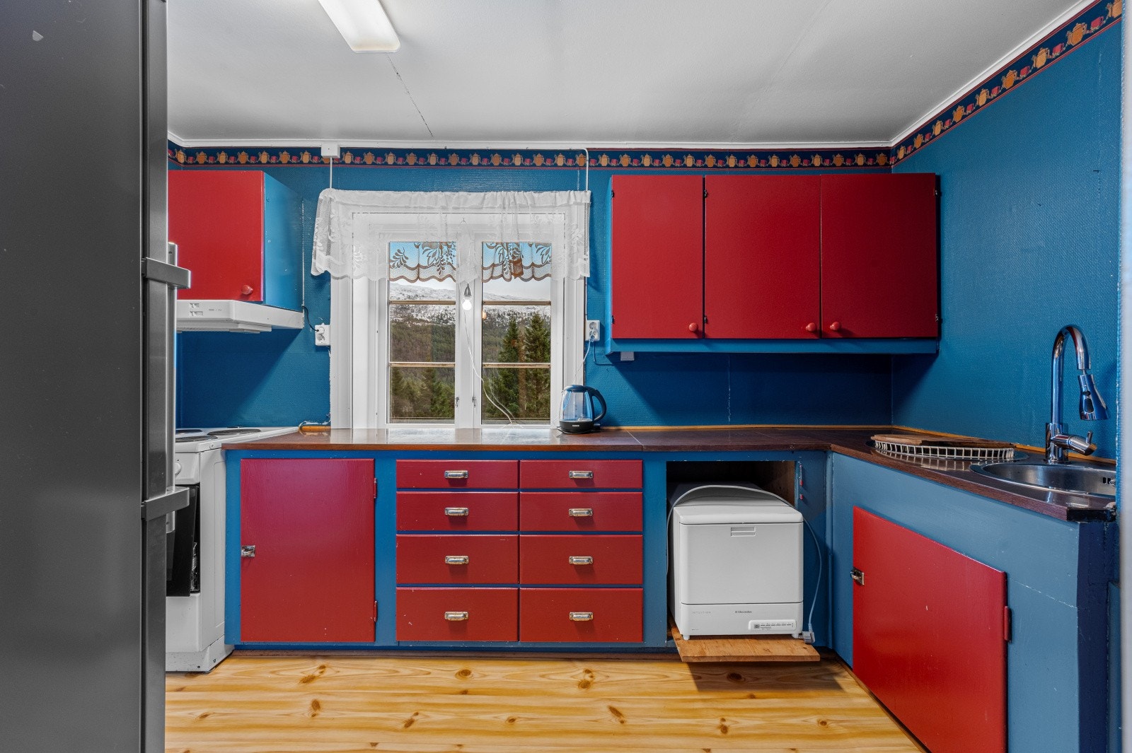 Eldre kjøkkeninnredning med malte fronter og benkeplate i laminat. Galleribilde