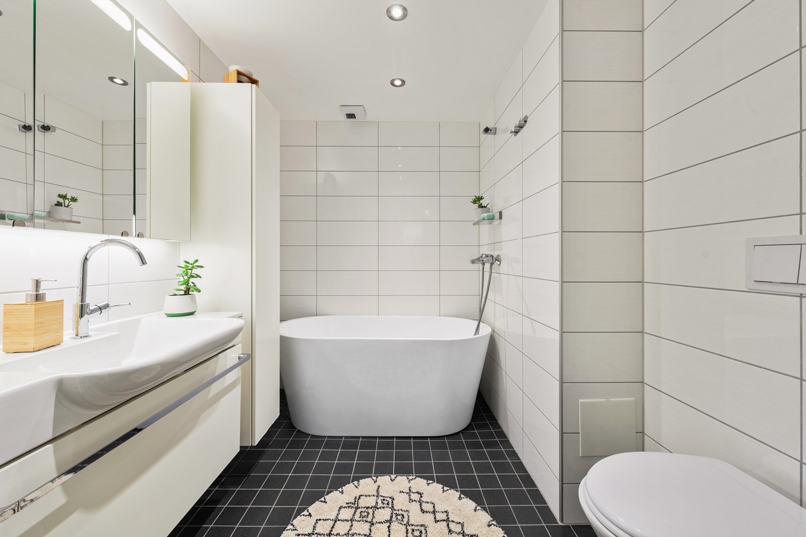 Baderom 2 er innredet med moderne badekar fra 2021 med integrert dusjløsning, stilren servant med praktisk underskap og matchende speil, samt et pent plassert toalett. Badekaret er frittstående og kan enkelt fjernes ved behov. Galleribilde