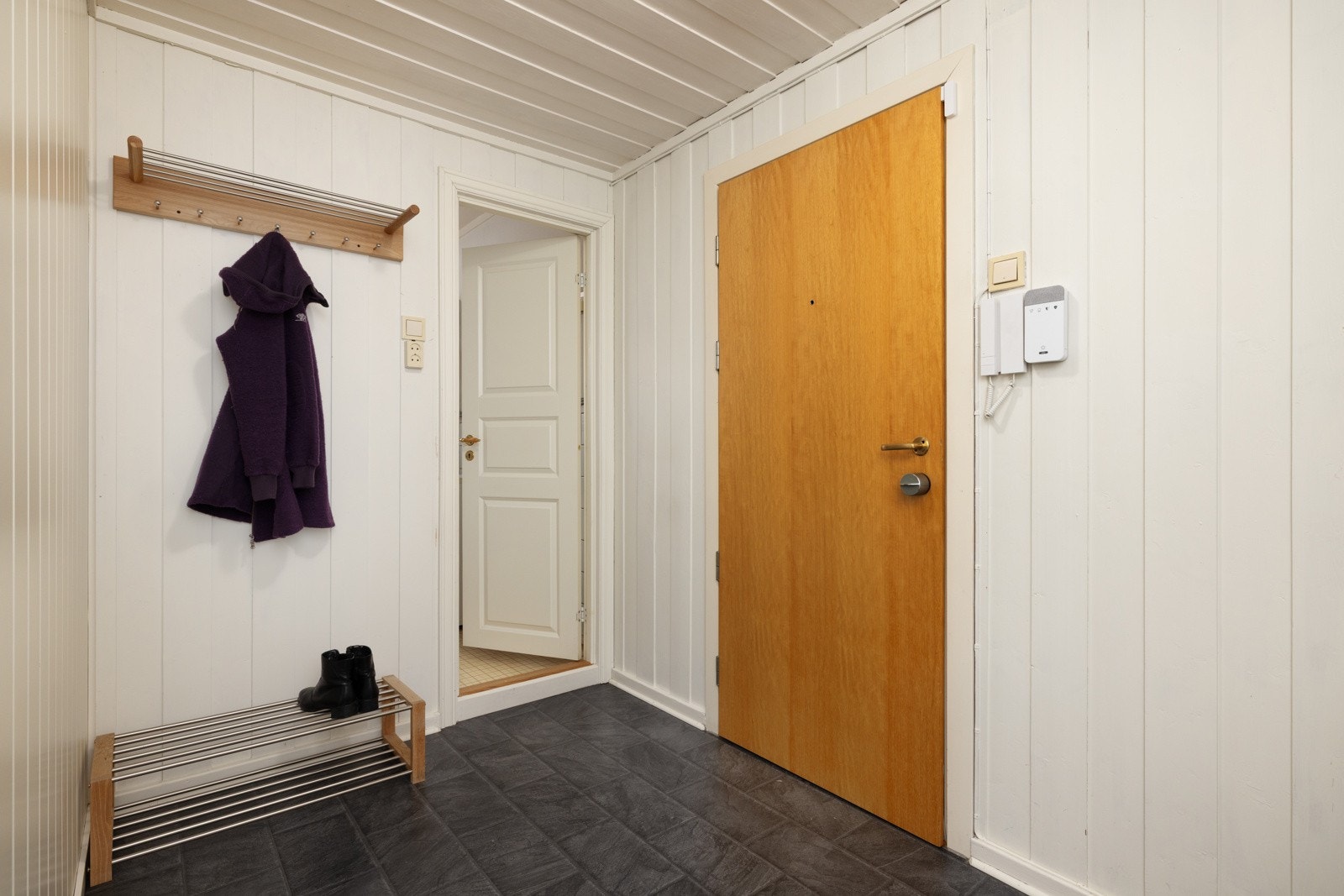 Lys og romslig entré med oppheng for klær og sko. Inngang til bad. Galleribilde