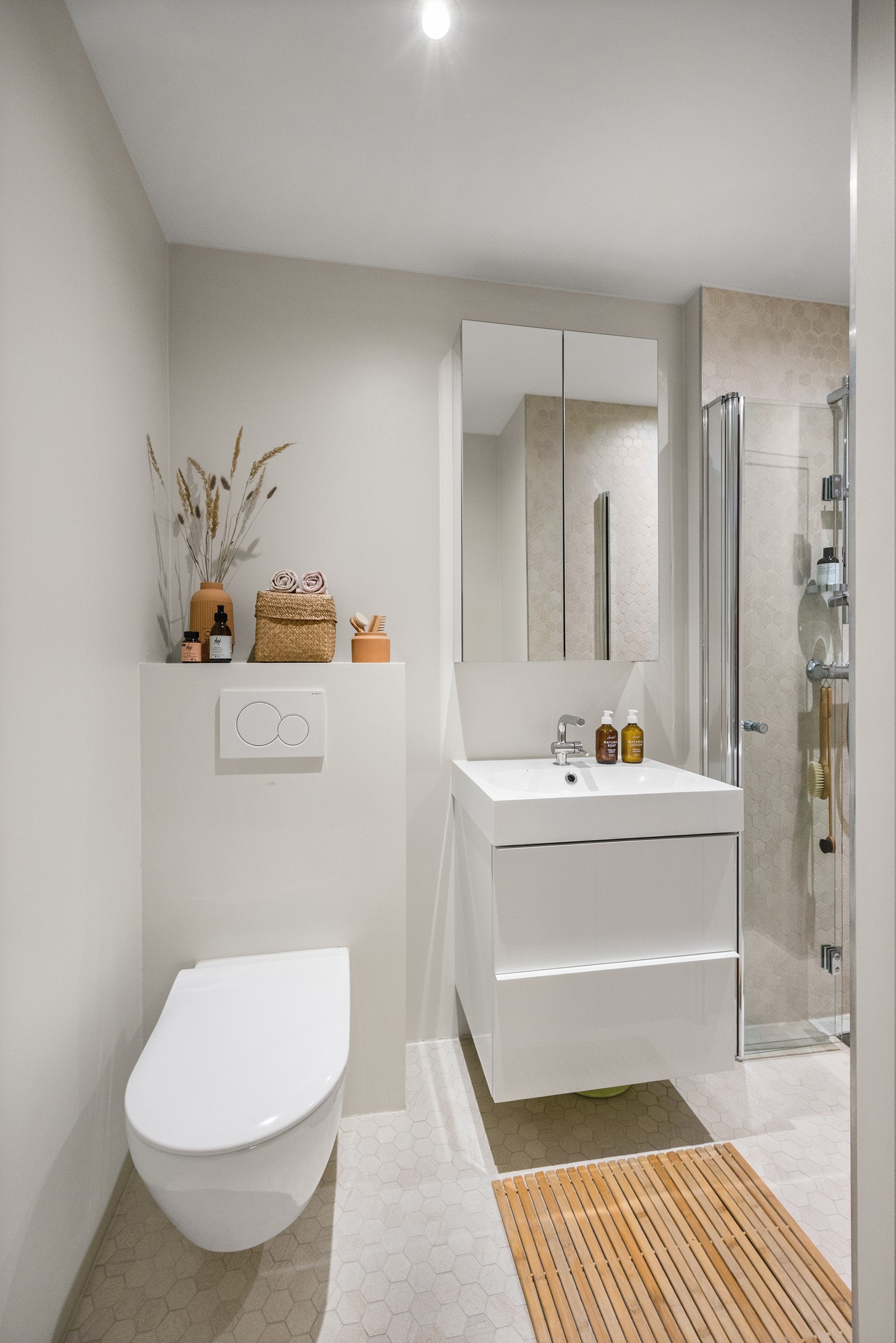 Flislagt bad med varmekabler, dusjnisje, veggmontert servantskap og toalett Galleribilde