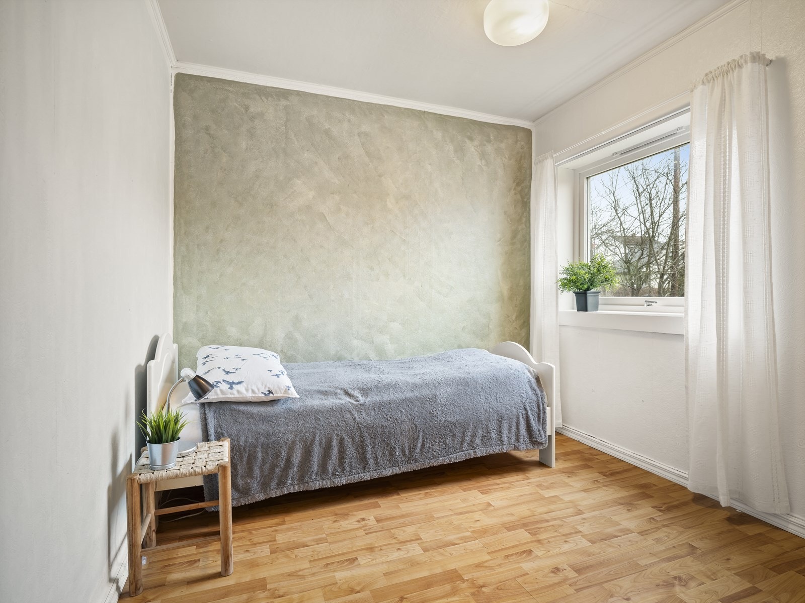 Soverommet i første etasje er lyst med malte vegger og stort vindu Galleribilde