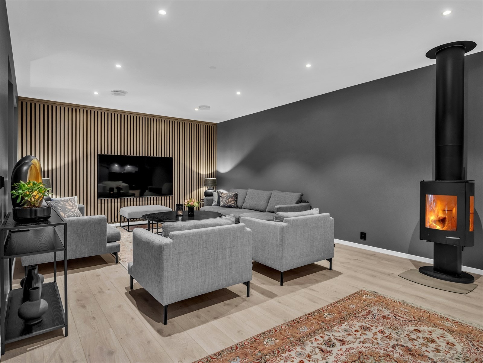 Sofahjørnet har en moderne spilevegg bak TV-en, som gir en varm og fin brytning til de ellers glatte veggene. Det er god plass til en stor lounge med plass til hele familien. Galleribilde