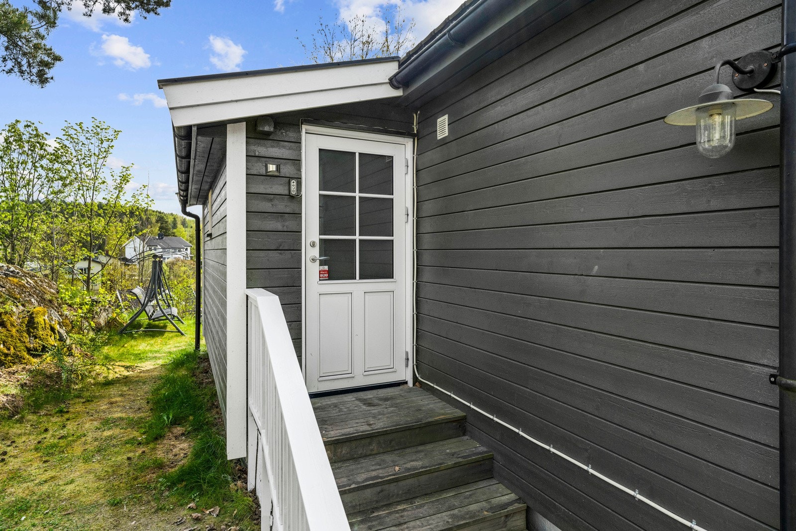 Boligen har et pent inngangsparti med trapp i tre og veggmontert utebelysning. Galleribilde