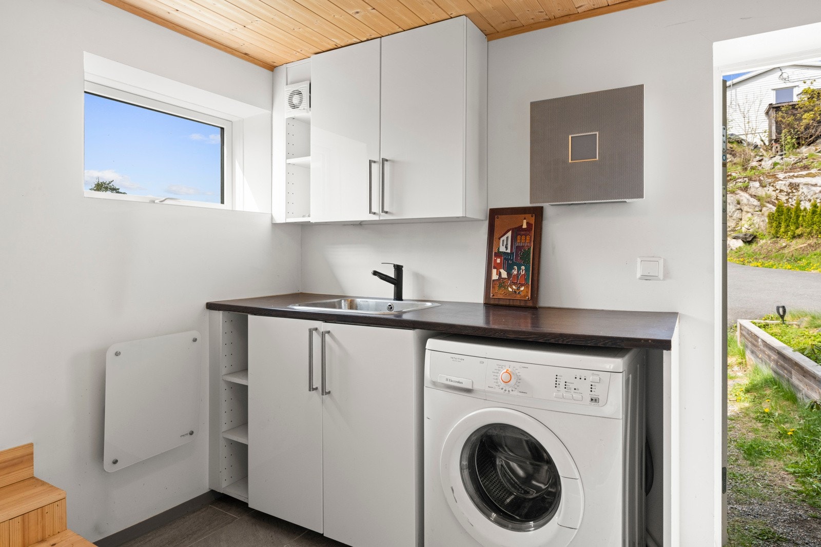 Kjellerrommet er innredet med hvite over- og underskap og en mørk laminatbenkeplate med nedfelt kum - alt fra 2022. Galleribilde