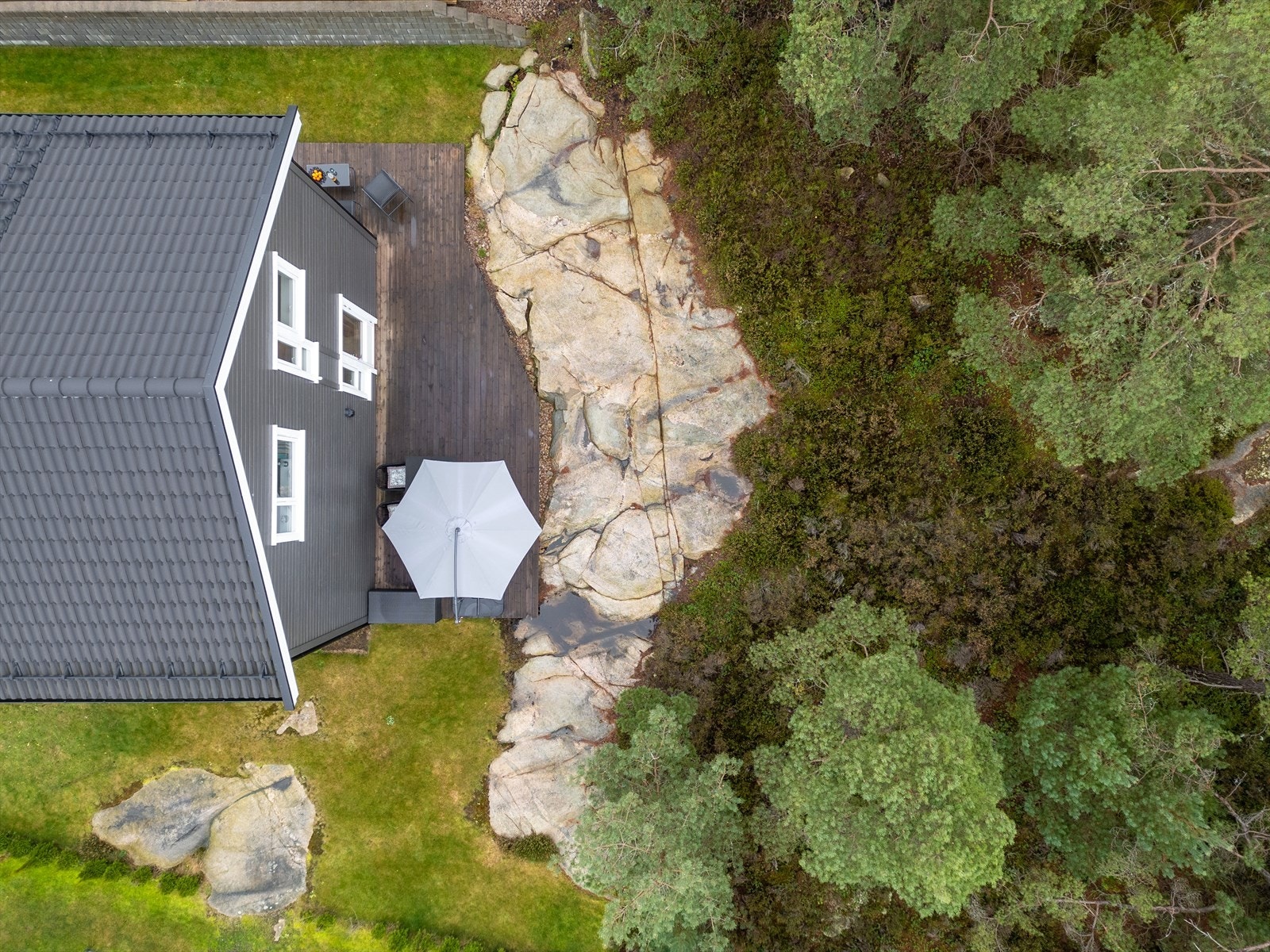 Langs husveggene er det opparbeidet en jevn gressplen, og på baksiden foran de sørøstre og sørvestre veggene har man etablert en stor, fin platting med plass til ulike møblementer. Galleribilde