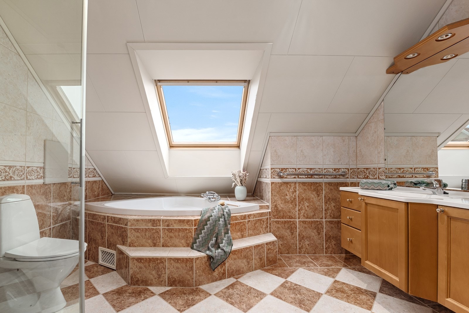 Bad med hjørnebadekar, dusj, toalett og baderomsinnredning. Galleribilde