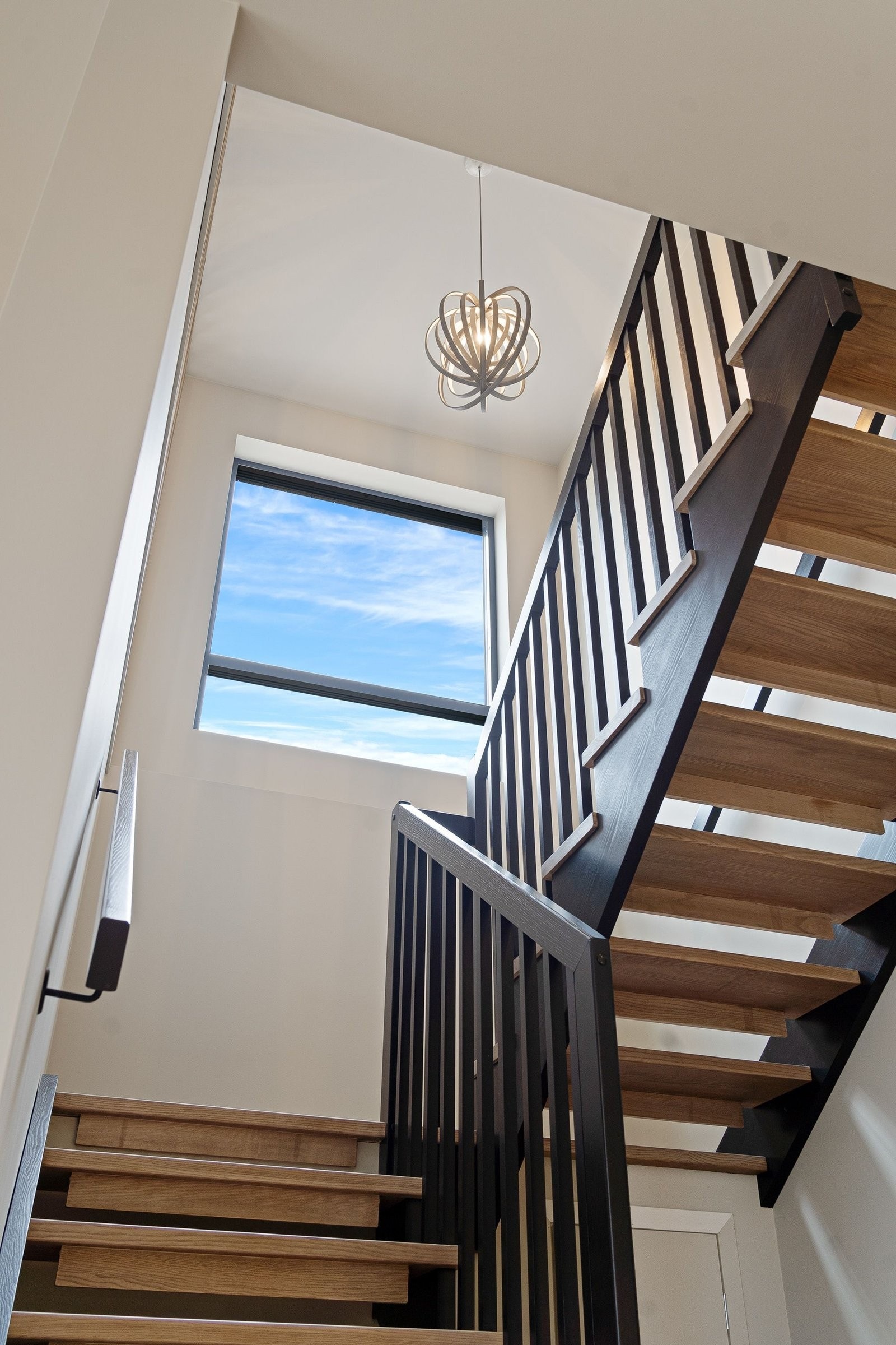 Lyst og trivelig trapperom med stort vindu. Trappetrinn og trapperepos i heltre ask kombinert med trappevanger/rekkverk i dempet sort Galleribilde