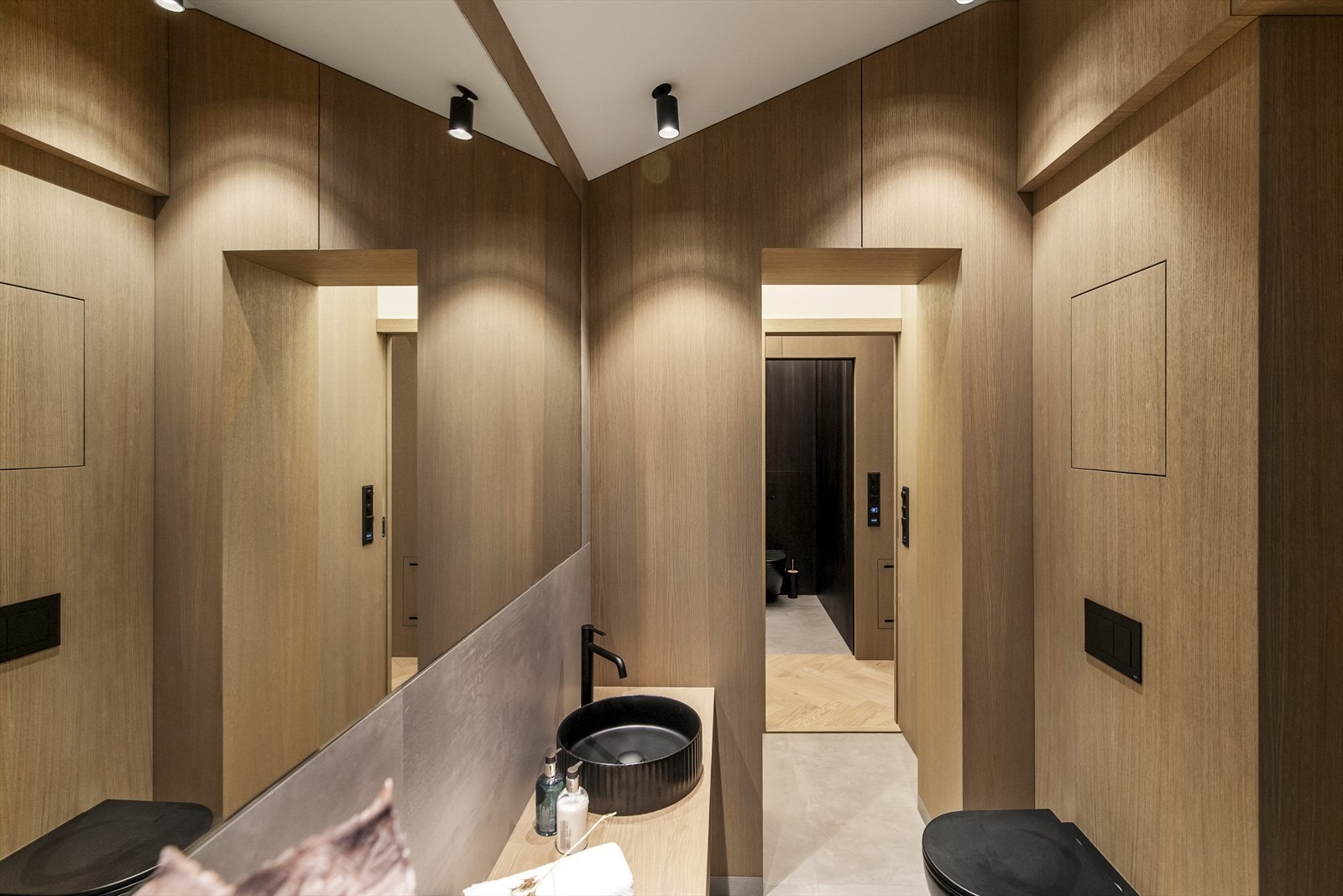 Varme er lagt i gulvet, og badet har sorte spotter i taket, vegghengt toalett i sort utførelse og opplegg for vaskemaskin i egen nisje. Dusjhjørnet er utstyrt med sort regnfallsdusj og innfellbare glassdører i sort innramming. Galleribilde