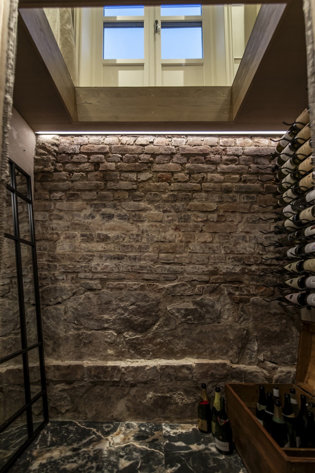 Vinkjelleren har innfelt belysning, original teglsteinsvegg og store, sorte gulvfliser i marmormønster. Galleribilde