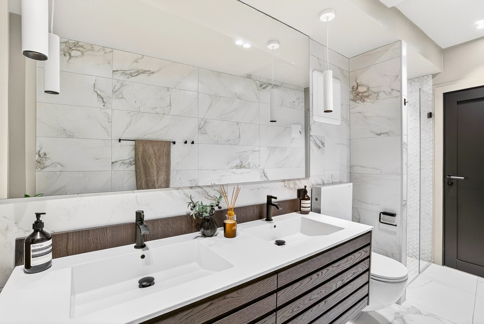 På badet er det vegghengt klosett, dobbel servant med underskap, dusjhjørne samt opplegg for vaskemaskin og tørketrommel Galleribilde