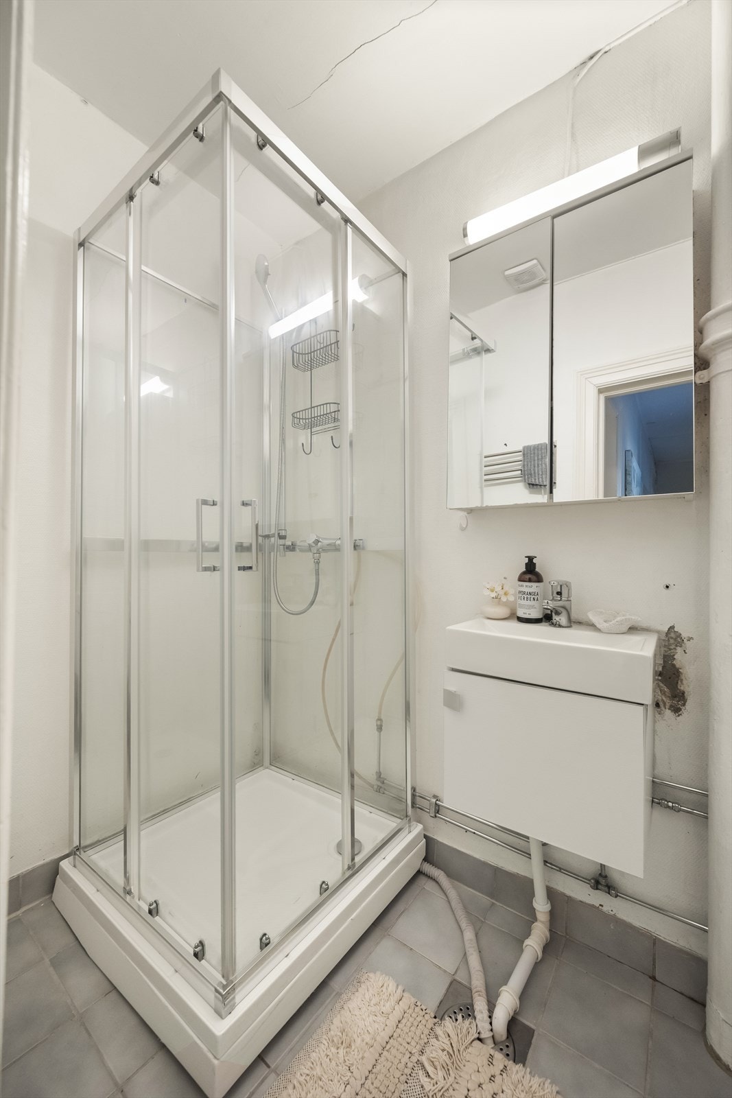 Badet er innredet med frittstående toalett, dusjkabinett og servant med ettgreps blandebatteri, skap og speilskap. Galleribilde