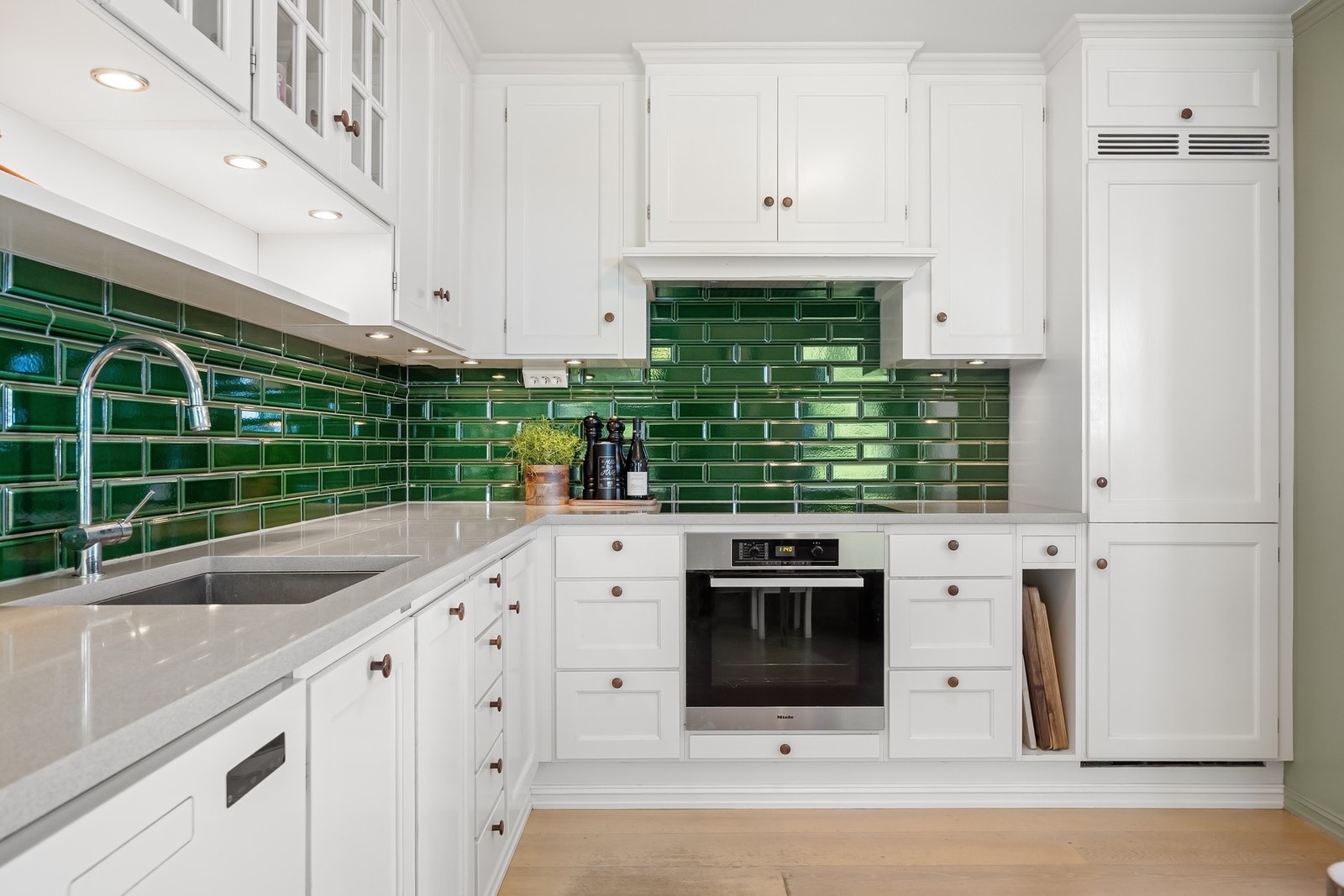 Kvalitets- og innholdsrikt Kvänum-kjøkken fra 2012 med lyse profilerte fronter og benkeplate av steinmateriale. Galleribilde