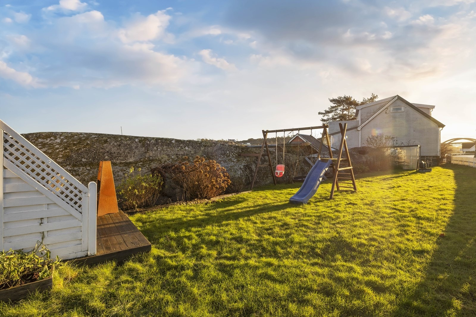 Den solrike hagen er pent opparbeidet med plen, lekestativ og et lite drivhus. Galleribilde