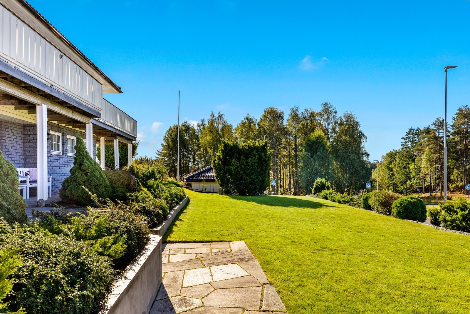 Eiendommen har en pent opparbeidet hage med plen og beplantning. Galleribilde
