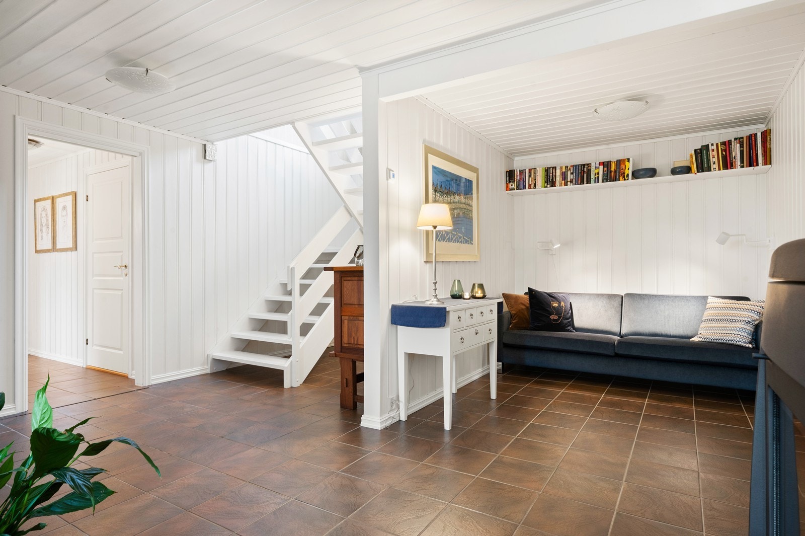 Underetasjen har en romslig hall med flislagt gulv og trapp opp til hovedetasjen. Galleribilde