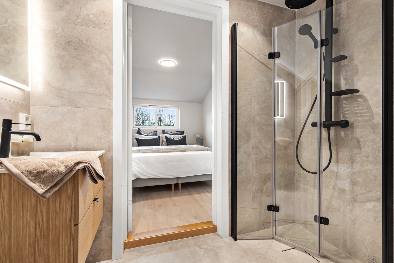 Badet har dusjhjørne med sorte detaljer, regndusj og innfellbare dusjdører Galleribilde