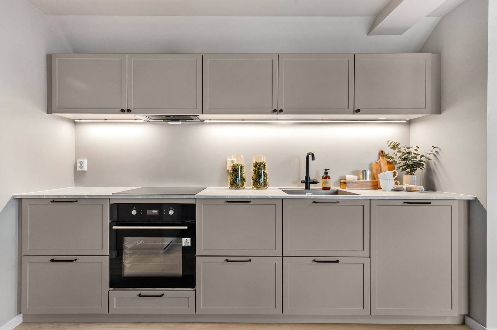 Innredning har integrerte hvitevarer, herunder kjøl/fryseskap, oppvaskmaskin, induksjonstopp og stekeovn Galleribilde