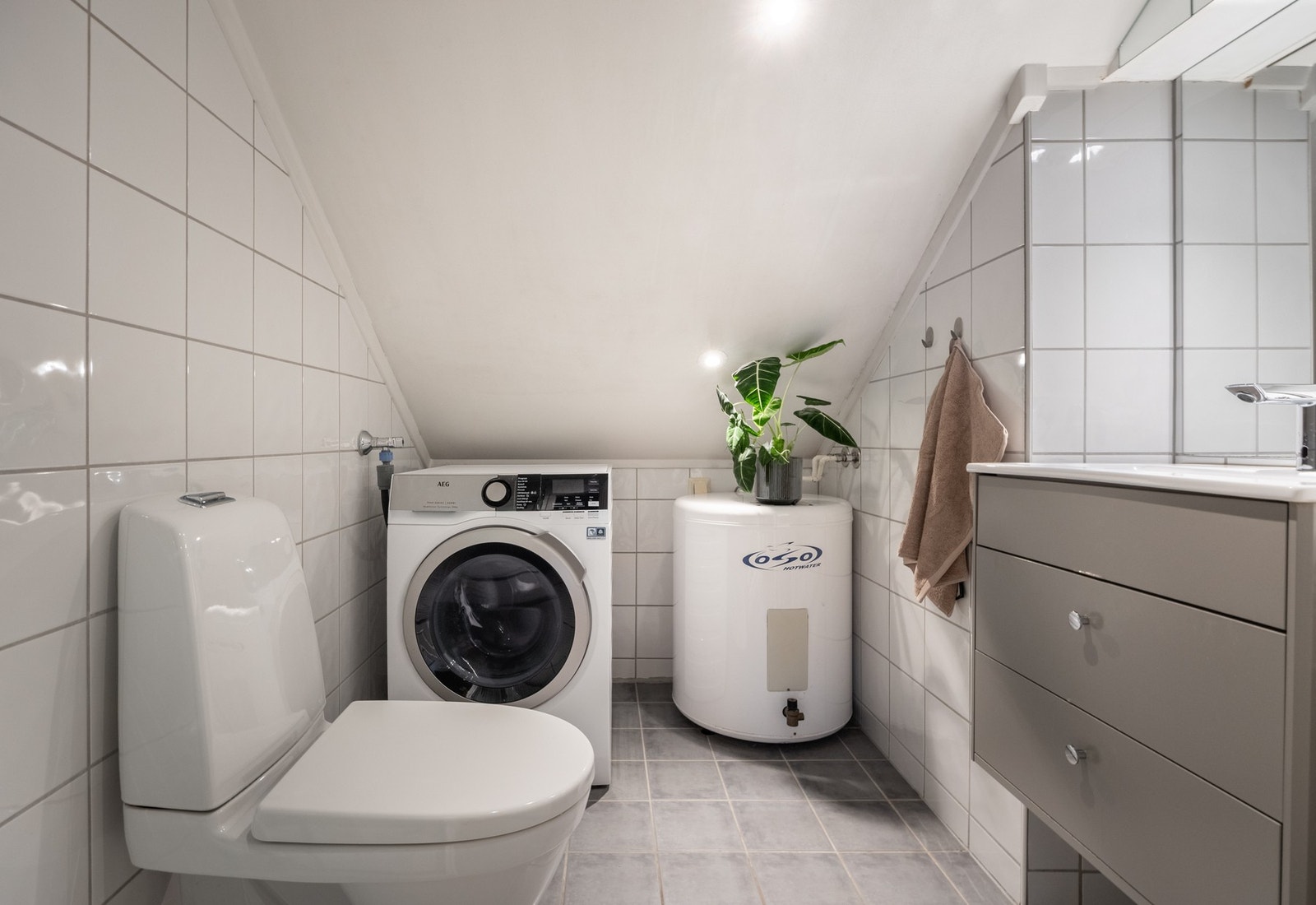 Badet har flislagt gulv med gulvvarme og opplegg for vaskemaskin. Galleribilde