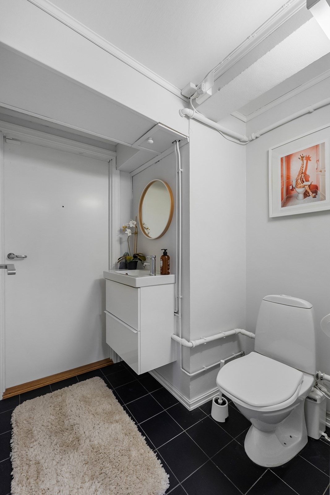 Toalettrommet i kjeller har flislagt gulv og servantskap med tilhørende speil. Galleribilde