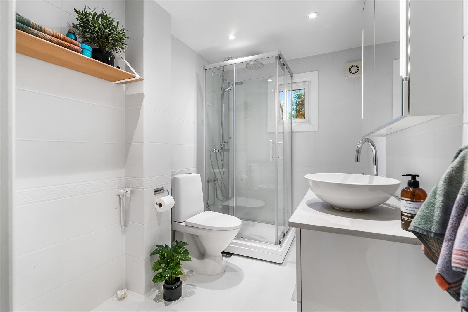 Badet ligger på hovedplanet, og i kjelleren har leiligheten et ekstra wc-rom. Hvite gulvfliser kombineres med lysegrå fliser på baderomsveggene. Galleribilde