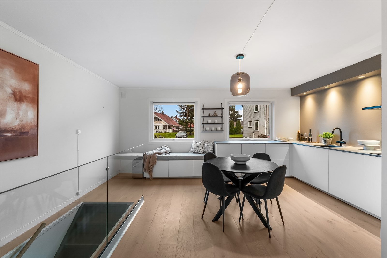 Innredningen er stilren og moderne, med hvite, glatte fronter, hendige høyskap, nedfelt oppvaskkum og lysegrå benkeplate av laminat. Galleribilde