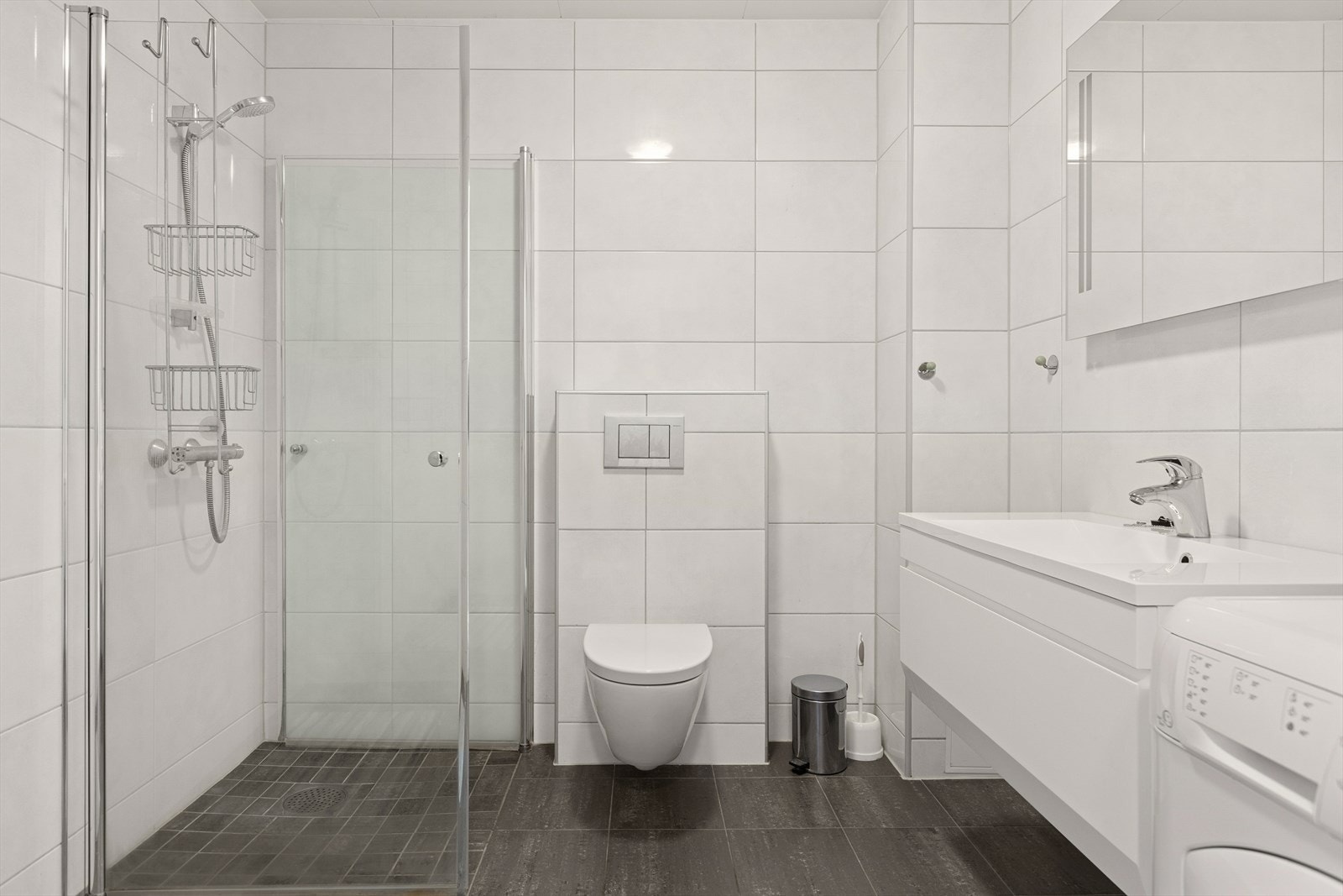 Badet er utstyrt med blant annet vegghengt servant og toalett, opplegg for vaskemaskin samt et praktisk dusjhjørne med innfelbare dører som gir ekstra gulvplass når dusjen ikke er i bruk. Galleribilde