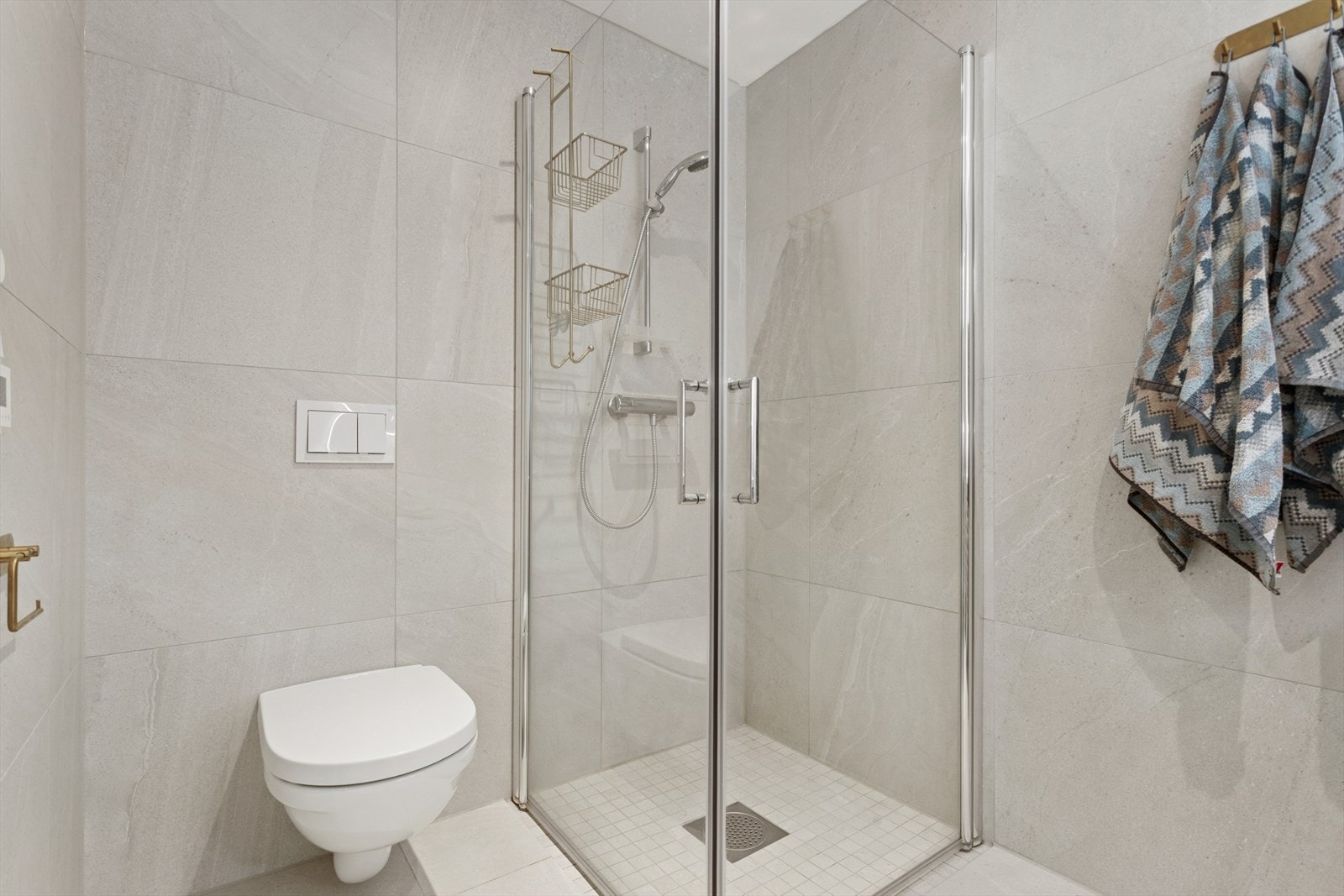 Badet er utstyrt med nedsenket dusjhjørne og vegghengt toalett. Galleribilde