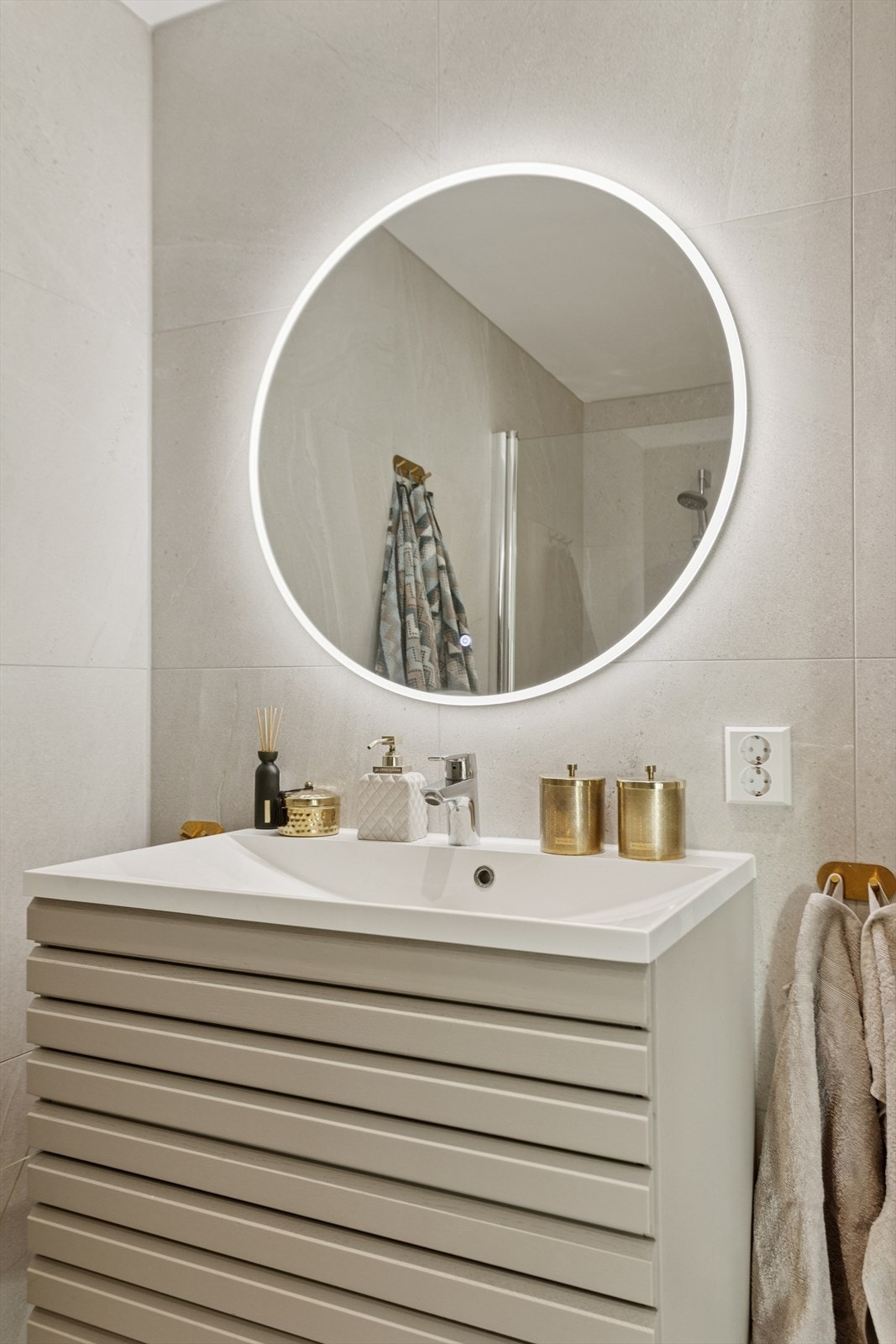 Pen innredning med heldekkende servanttopp og speil med tilhørende belysning. Galleribilde