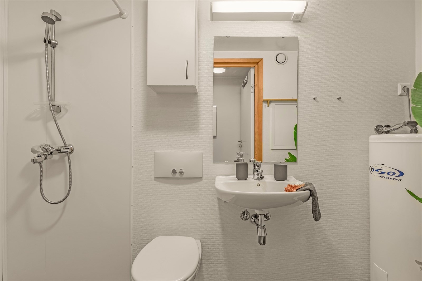 Enkel innredning på bad med vask, toalett og dusj mm Galleribilde