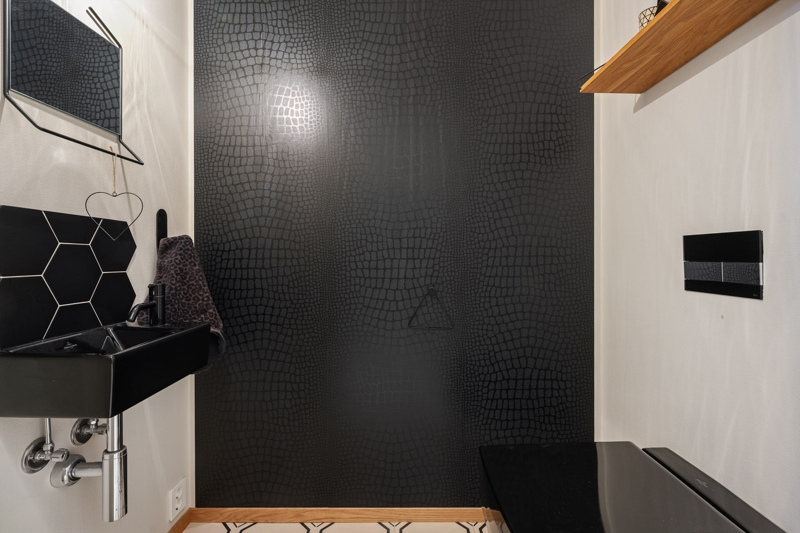 Toalettrommet har fliser på vegger og gulv, samt malt innvendig tak. Det er utstyrt med vegghengt toalett og servant. Galleribilde