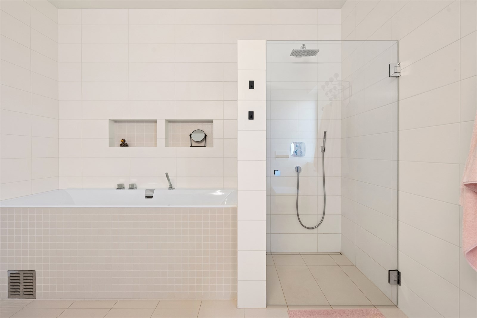 Dusjnisje med glassdør og stedsbygget badekar kompletterer rommet. Galleribilde