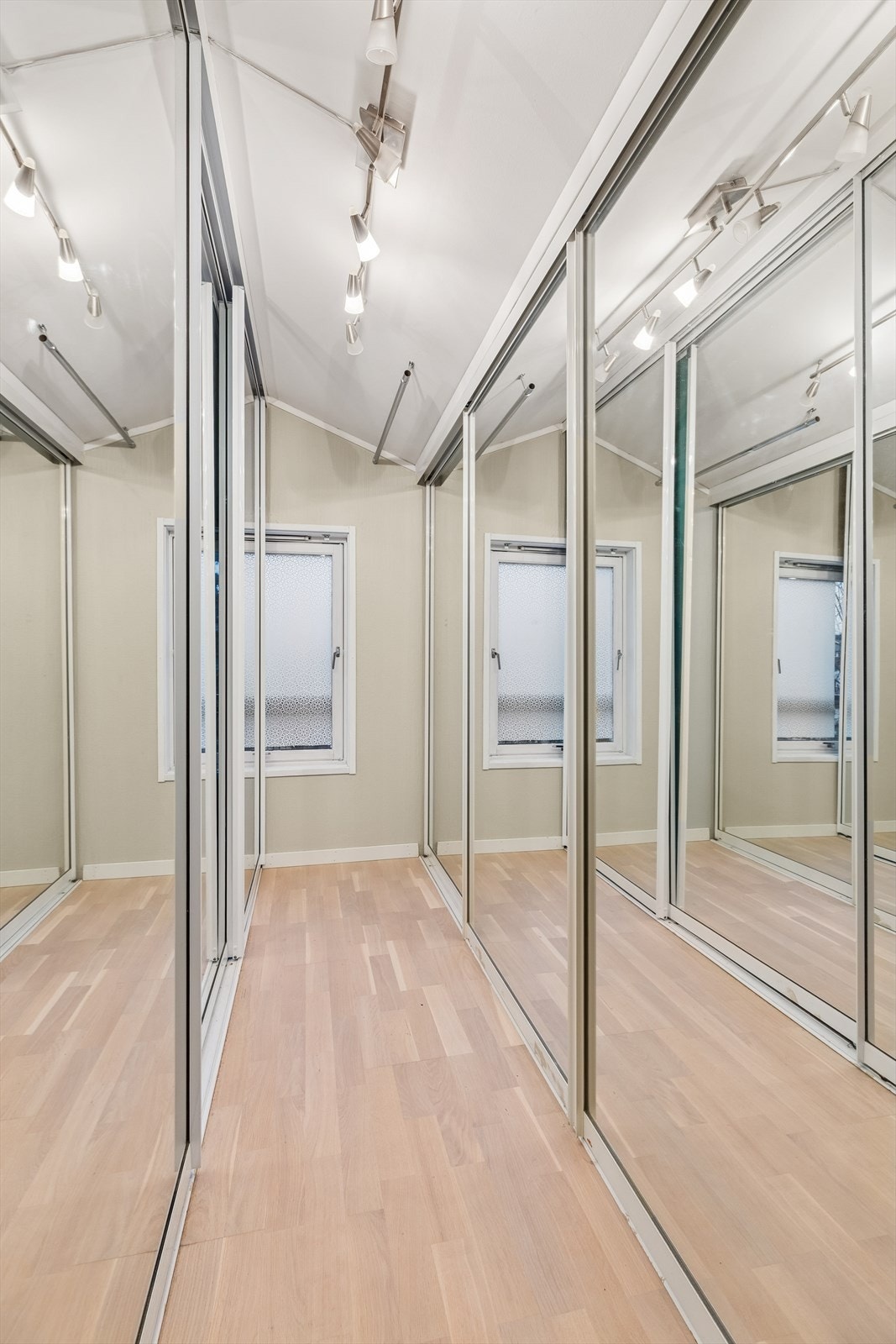 Omkledningsrom, innredet med plassbesparende skyvedørsgarderobe på to sider av rommet. Galleribilde