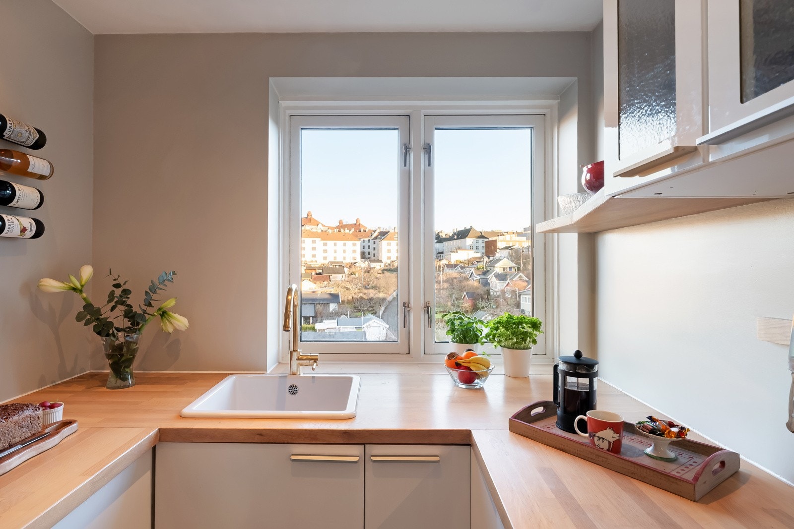 Kjøkkeninnredning med lyse glatte fronter og benkeplate med nedsenket oppvaskkum. Galleribilde