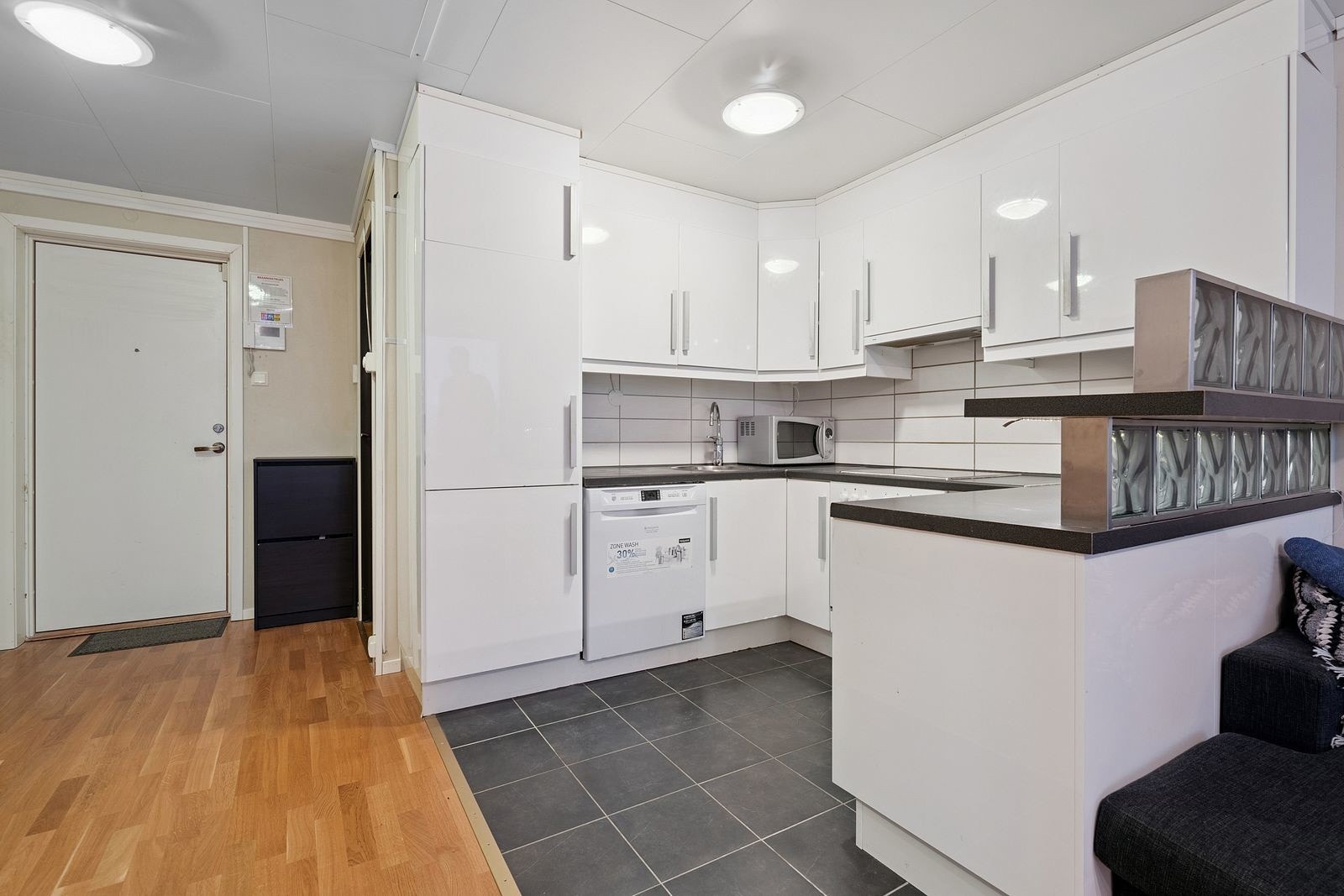 Kjøkken i tidløse farger, med integrert kjøleskap og flislagt gulv. Galleribilde