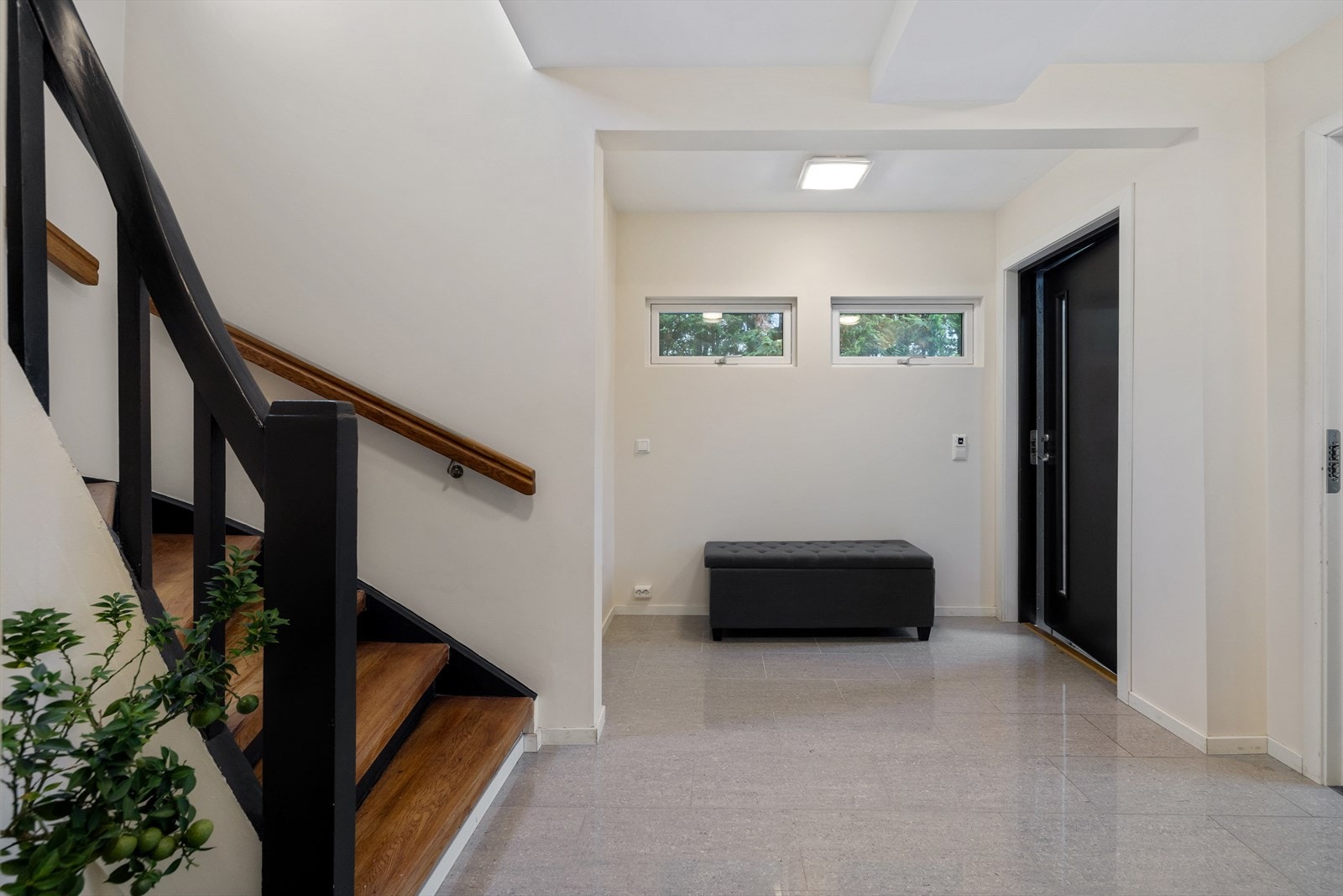 Den gråflisede gangen har lyse fine vegger, og et luftig trapperom. Galleribilde