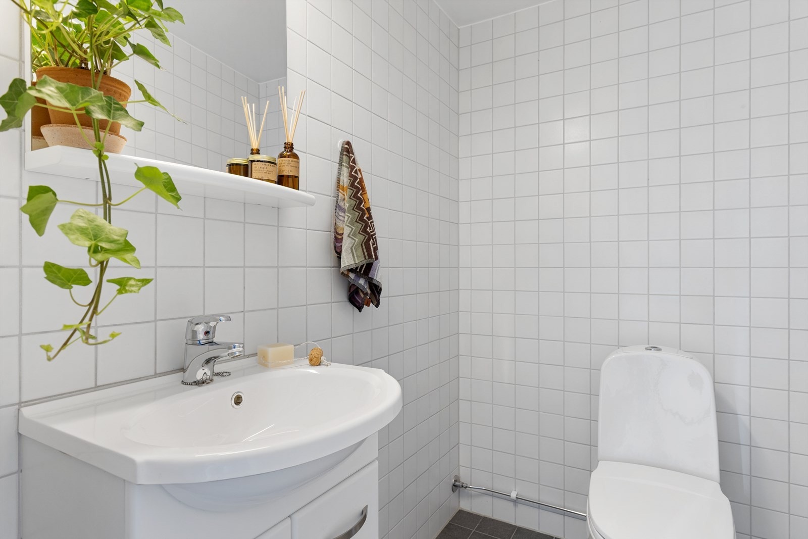 Flislagt toalettrom med gulvstående toalett og servantinnredning med ett-greps blandebatteri. Galleribilde