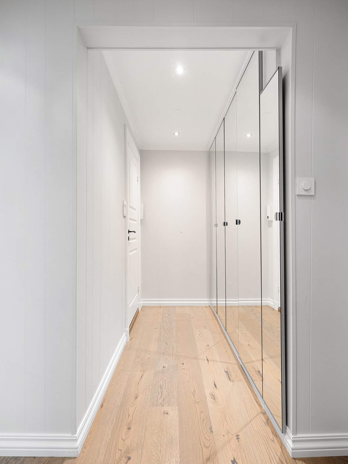 Gangen har downlights i himling og gode oppbevaringsmuligheter i integrerte garderobeskap med speilfronter Galleribilde